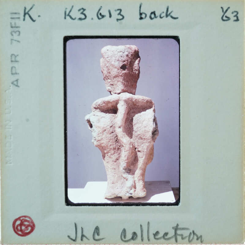 Ancient clay figurine with a humanoid shape, showing back with braids.