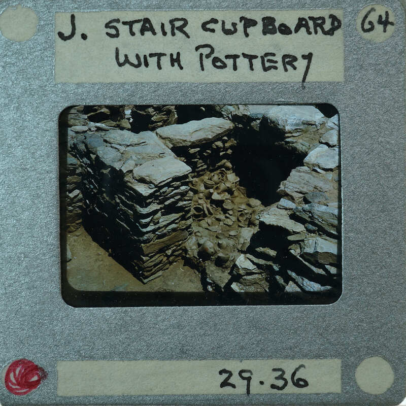 A vintage photo of a stone structure with a handwritten label on the back.