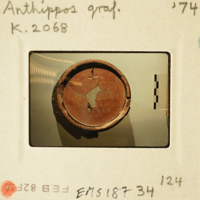 Ancient artifact with visible cracks and wear, photographed on a white surface.