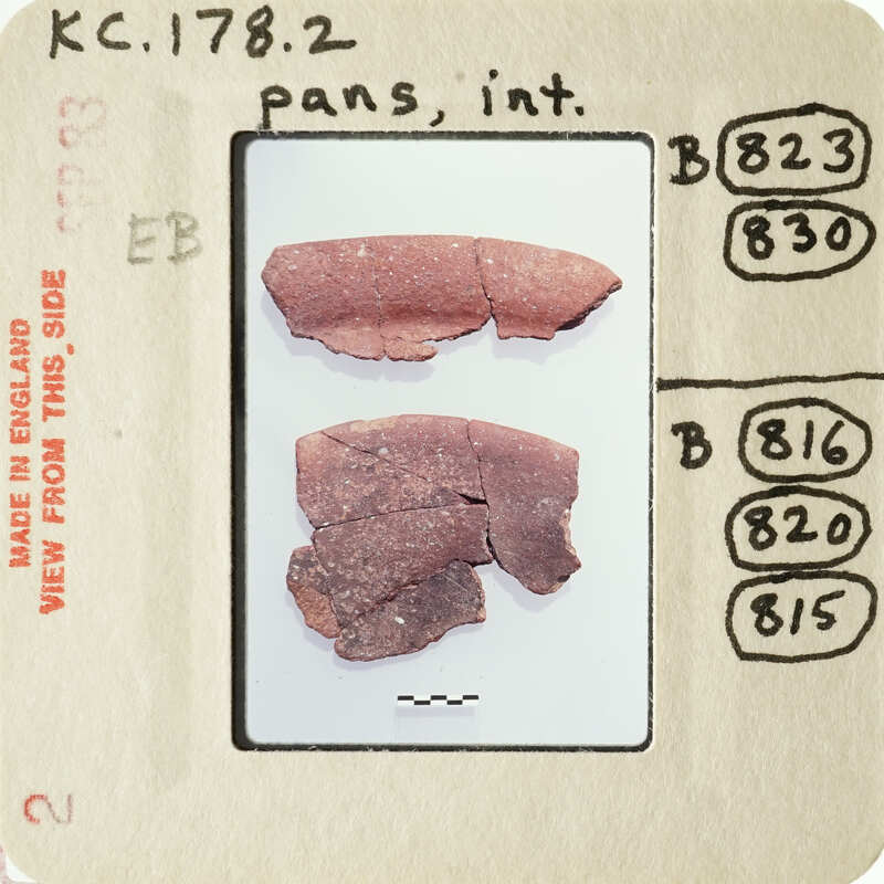 Photograph of two broken red ceramic pieces with visible cracks and missing parts, displayed on a white surface.