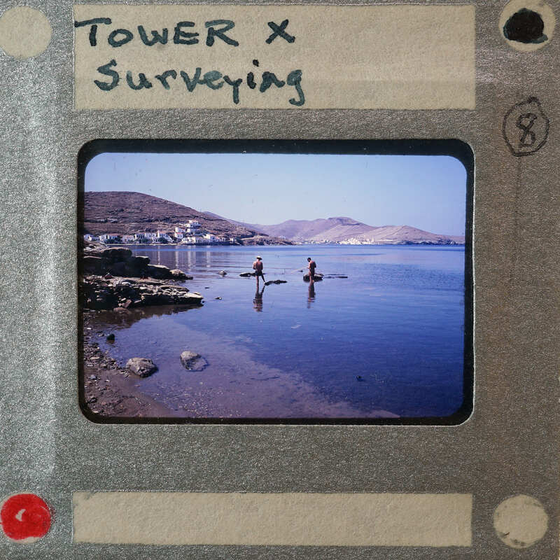 Picture of two people standing on a beach with mountains and water in the background, framed within an old-fashioned film strip border.