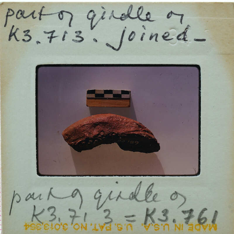 A close-up photograph of a rock specimen with a label attached to it, possibly from an educational or scientific collection.