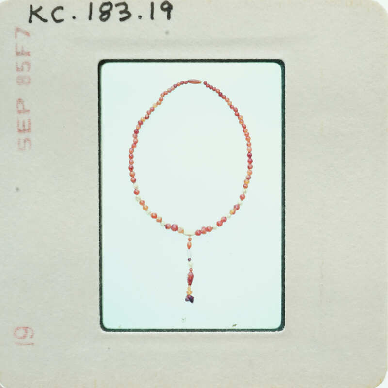 A vintage image of a bead necklace with a tassel on an old postcard.