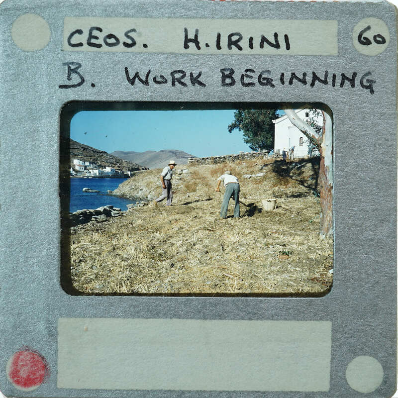 A vintage photograph of two people working on a farm, with mountains and water in the background.