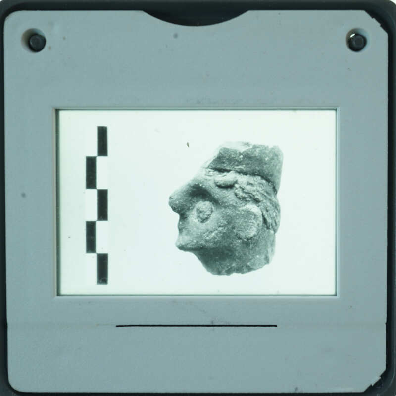 Small stone sculpture of a face displayed on a screen with measurement lines.