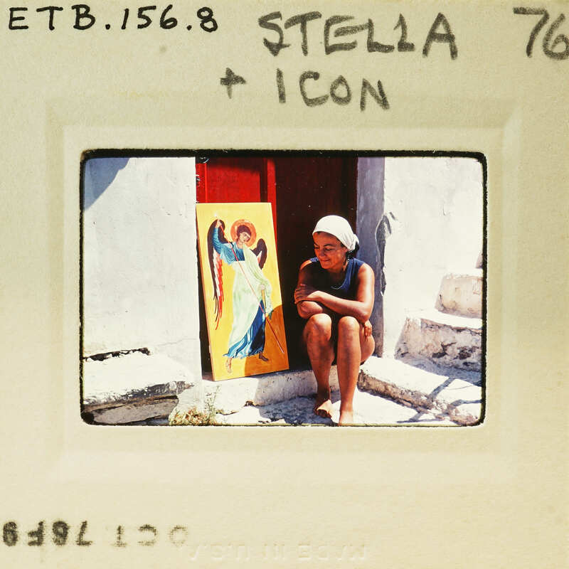 A woman sitting on steps with a religious icon behind her.