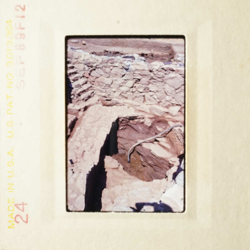 This photo shows an archeological site with stone ruins and a dirt floor.