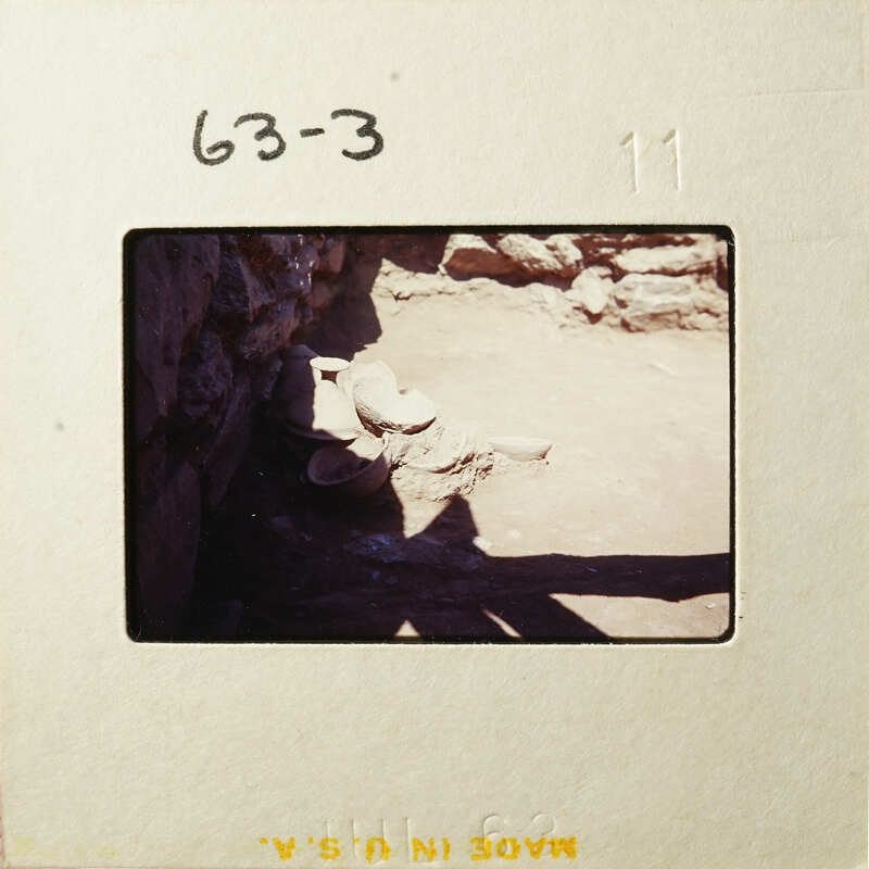 Old stone ruins with shadows and dirt ground.