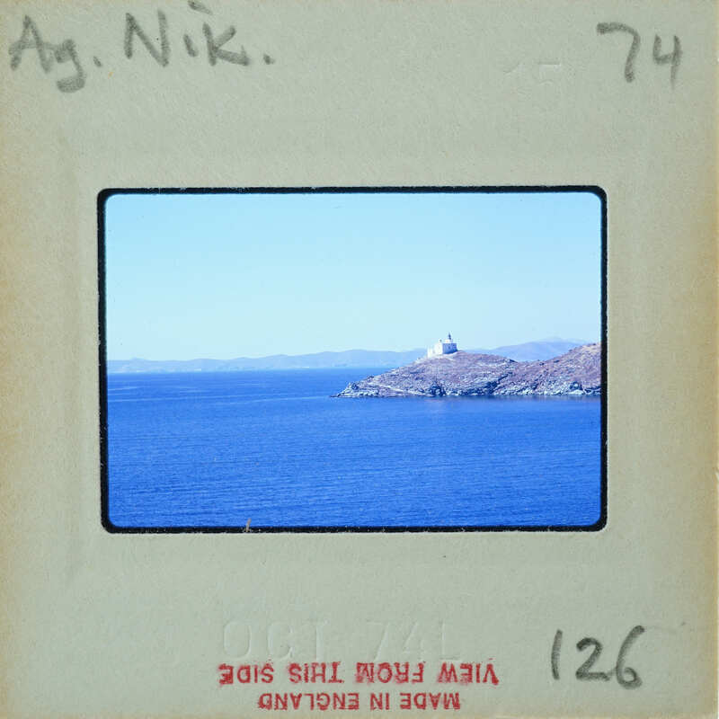 A photograph of a beautiful island with a lighthouse, taken from a distance and framed by an old film strip border.