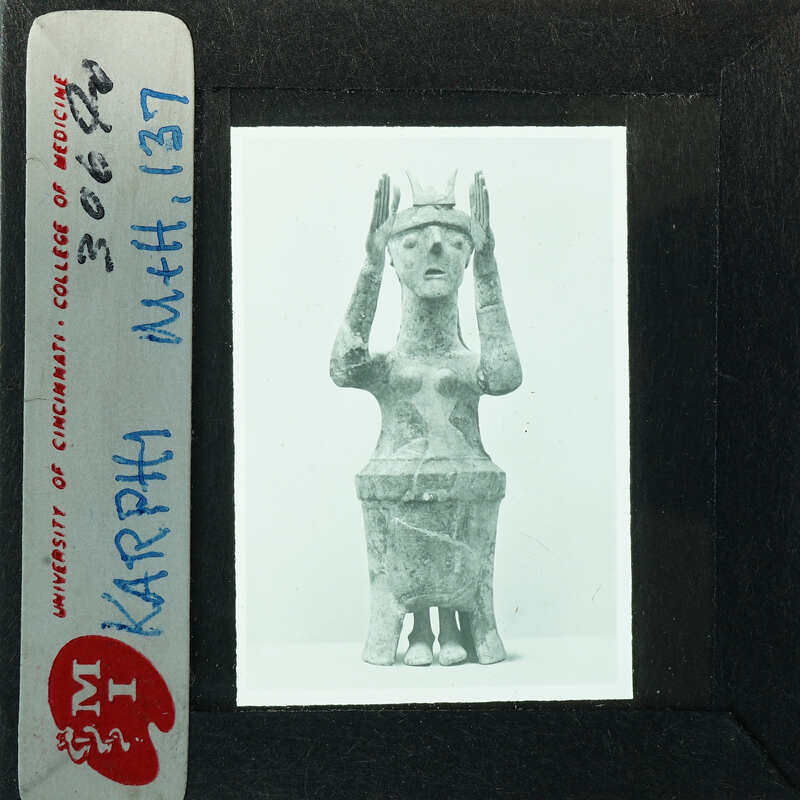 A photograph of an ancient sculpture, possibly a figurine or statue, with a label and stamp indicating it is from the Cincinnati Art Museum.