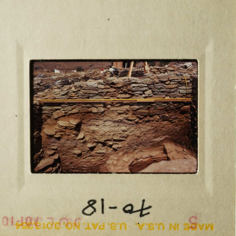 This is an image of a rock wall with a wooden structure on top, possibly indicating an archaeological site.