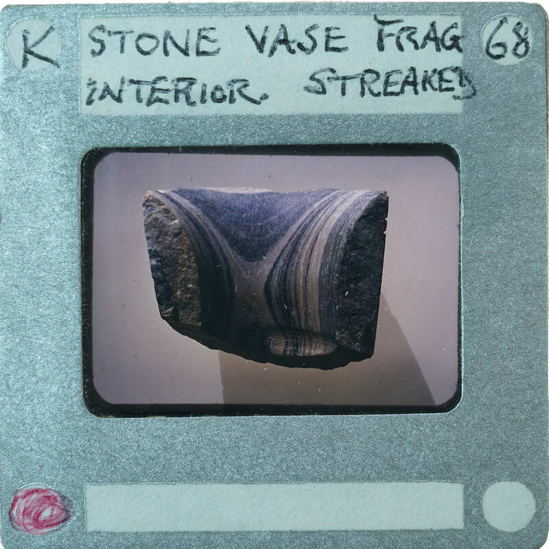 A photograph of a stone vase fragment with an intricate pattern on display.