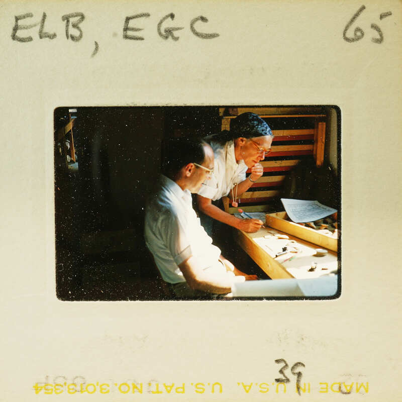 Two men sitting at a table with papers and pens, possibly working on a project or discussing something.