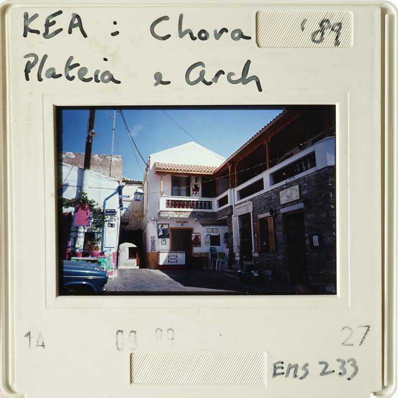A photograph of an old European village with white walls and brown roofs, taken from a balcony.
