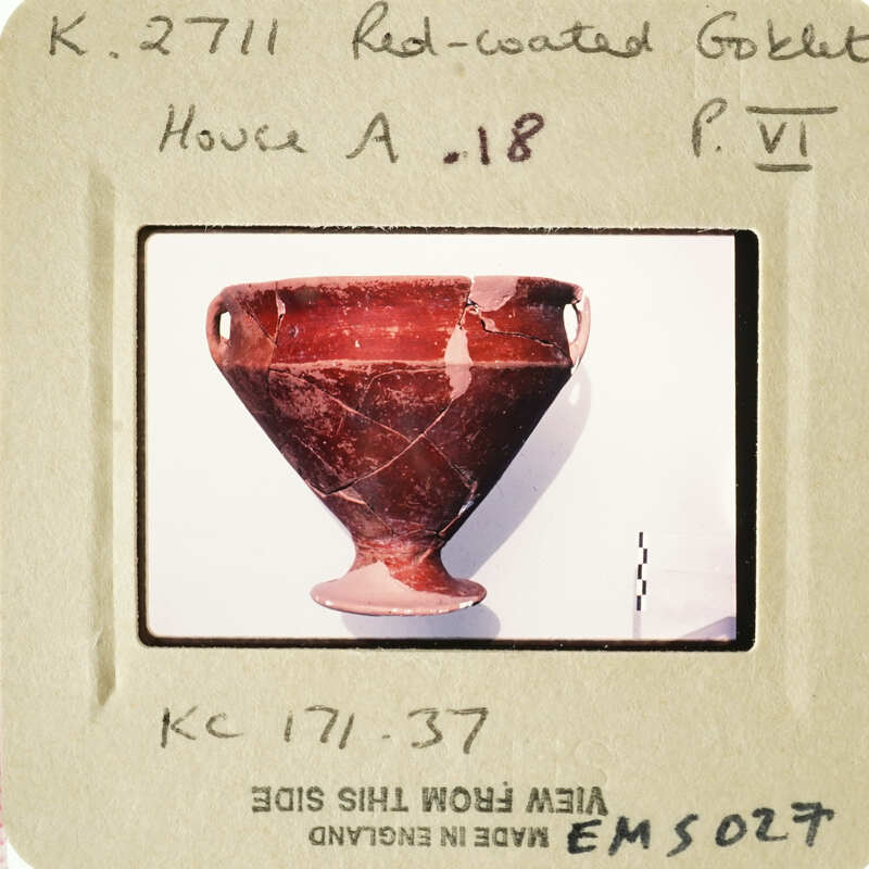 Ancient Greek vase with visible cracks and chips, displayed on a white stand.