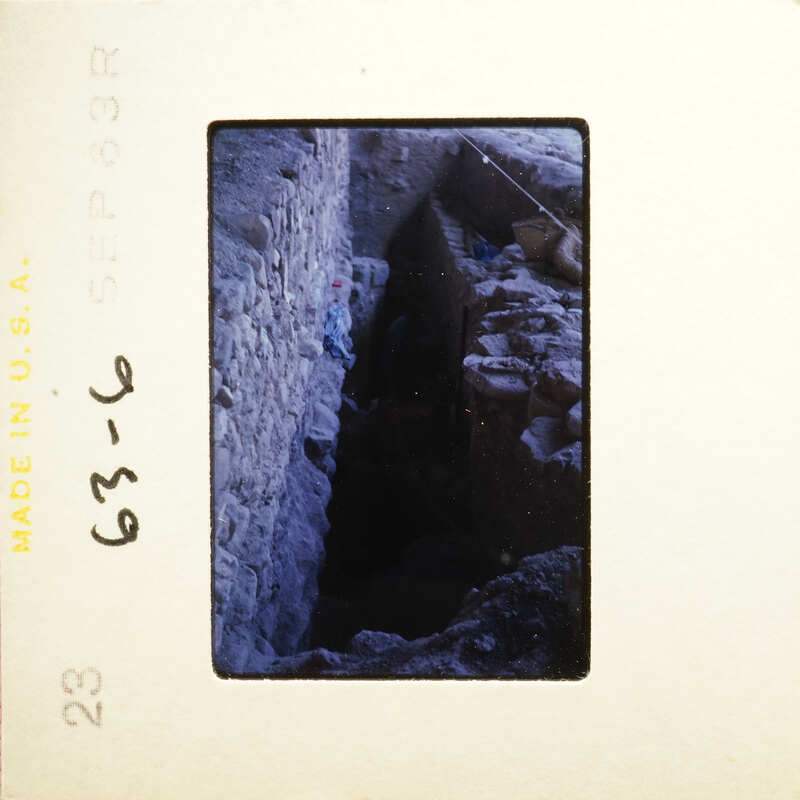 A dark, narrow tunnel with debris and an opening at the end.