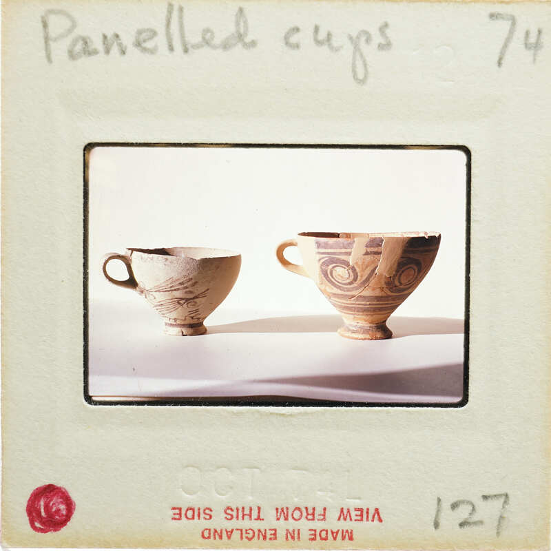Two panel cups with handles, side view.