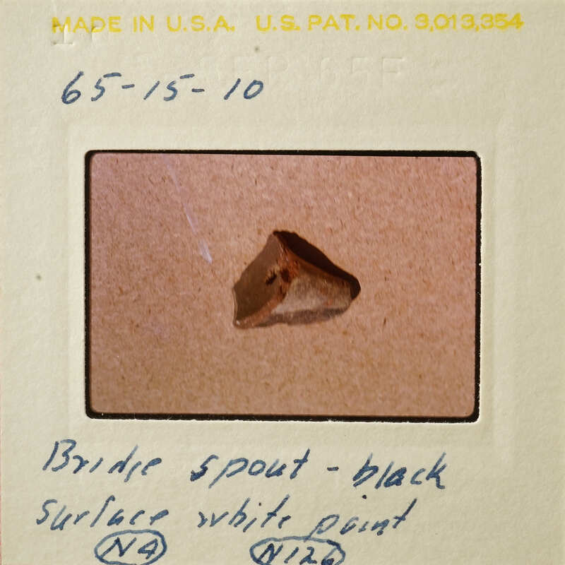 A small brown object on a white surface, possibly a bridge spout.