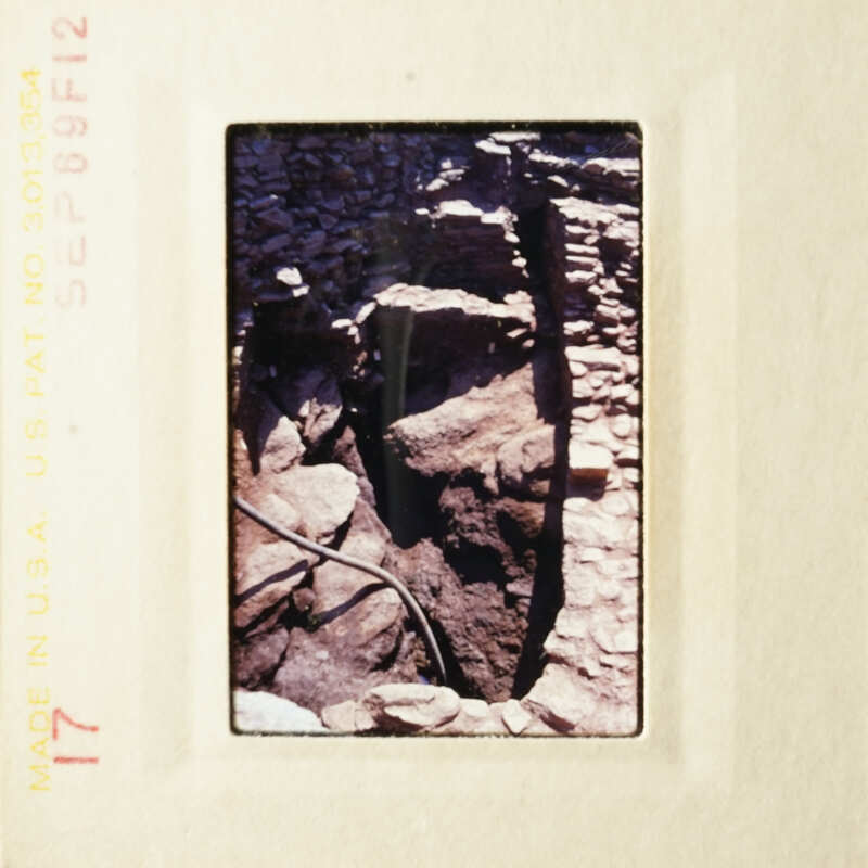 A photograph of an ancient stone structure with a rocky background, possibly ruins of an old building or wall.