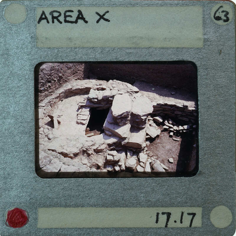 A photograph of an ancient stone structure with a face-like carving, taken on film and displayed in a vintage camera negative holder.
