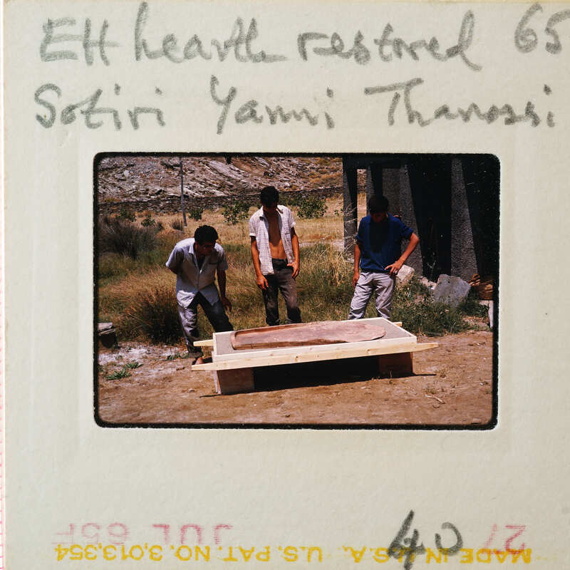 Three men working on a clay structure outdoors.