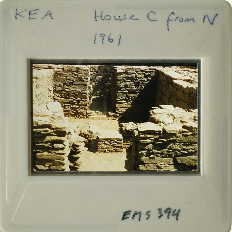 A photograph of an ancient stone structure, possibly ruins, with visible deterioration and vegetation growth.
