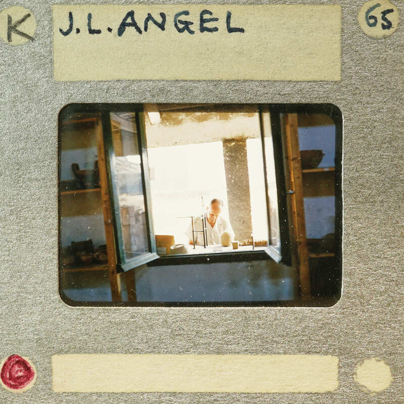 A vintage photo of a person sitting at a table with sunlight coming through the window.