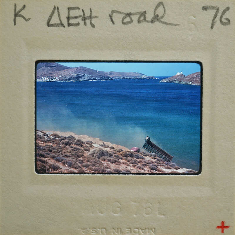 A photograph of a coastal landscape with a boat and mountains, taken on July 7th, 1976.