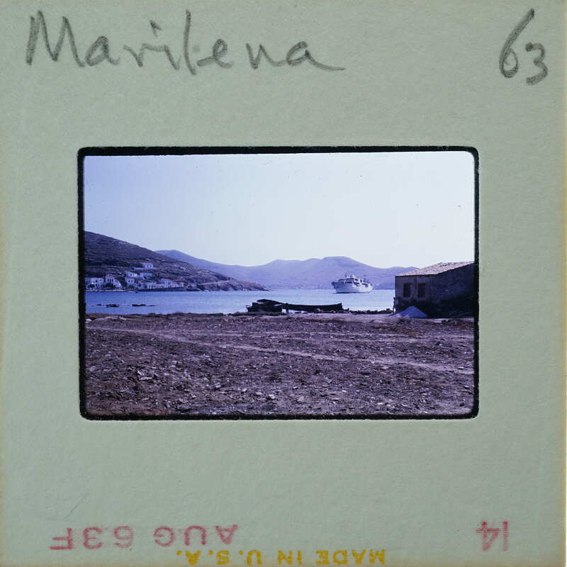 Photo of a coastal landscape with mountains, water, and buildings on a vintage film strip.