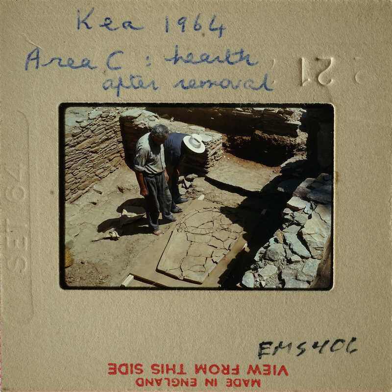 Two men working on an archaeological site with stone ruins and excavated areas.