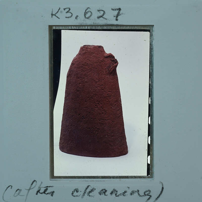 A photograph of a red artifact, possibly an ancient pottery piece, with cleaning instructions written on it.