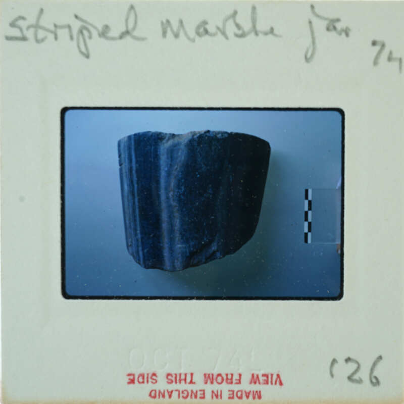 A close-up photograph of a blue rock with a label and identification number.
