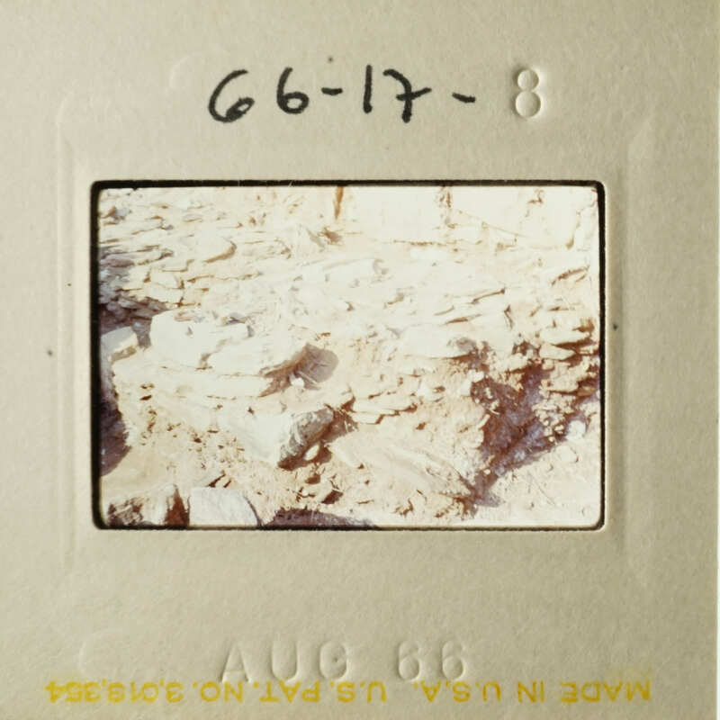 A vintage photograph of an outdoor scene with a pile of rocks and dirt, featuring handwritten notes on the border.