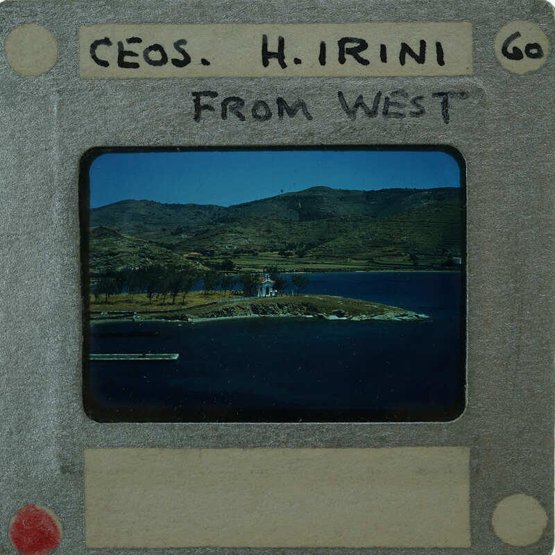 A photograph of a scenic landscape with mountains, water, and a small island, enclosed within an old-fashioned film clapperboard with handwritten notes.