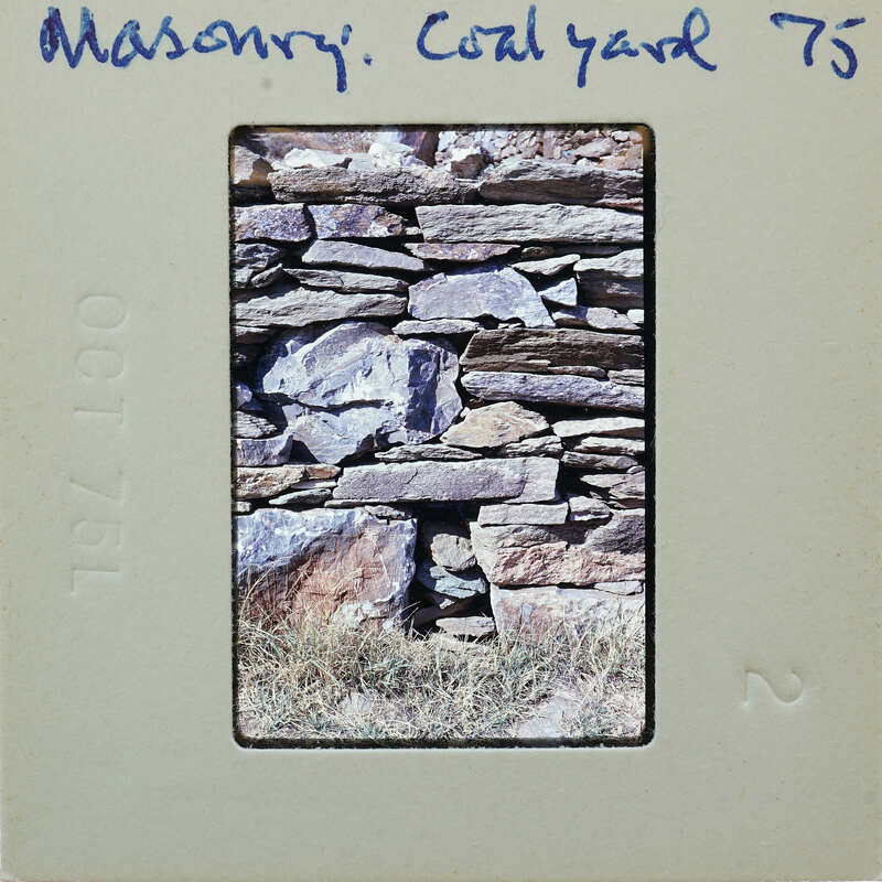 A vintage photograph of a stone wall with grass, labeled "Masonry, Coal Yard 75" on the border.