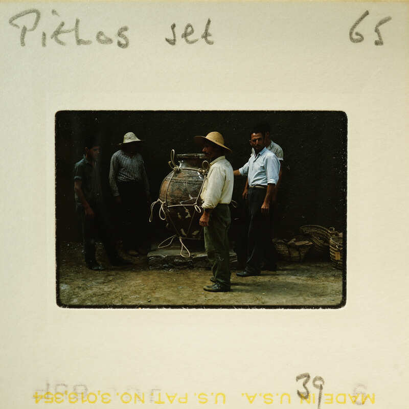 A vintage photograph showing a group of men standing around an old-fashioned steam engine.
