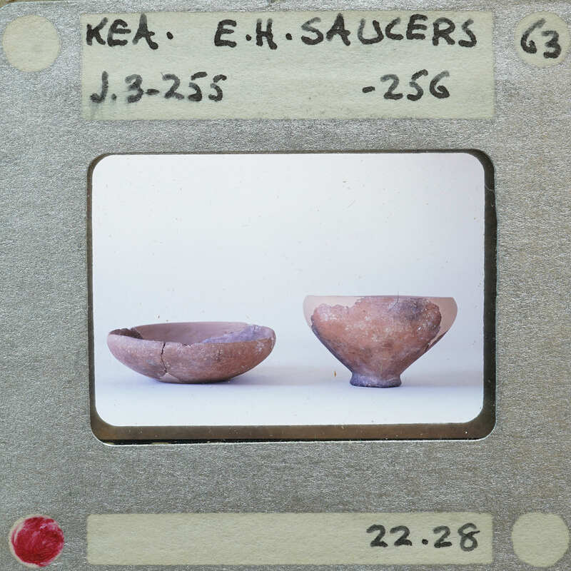 A photograph of two reassembled clay bowls on a white surface.
