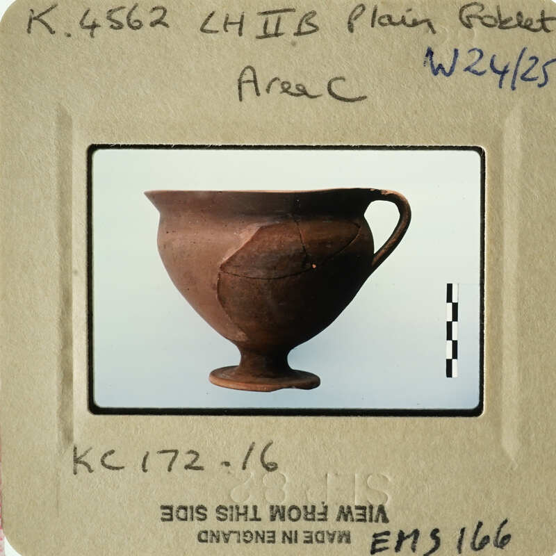 Ancient Greek vase with visible cracks and chips, displayed on a white surface.