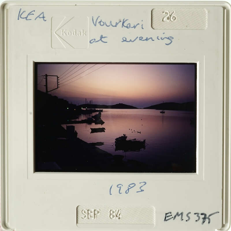 Sunset over calm water with boats and horizon line.