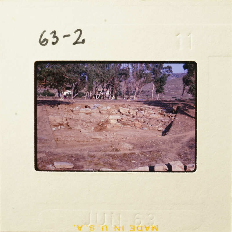 Ancient ruins with stone walls and trees in the background.