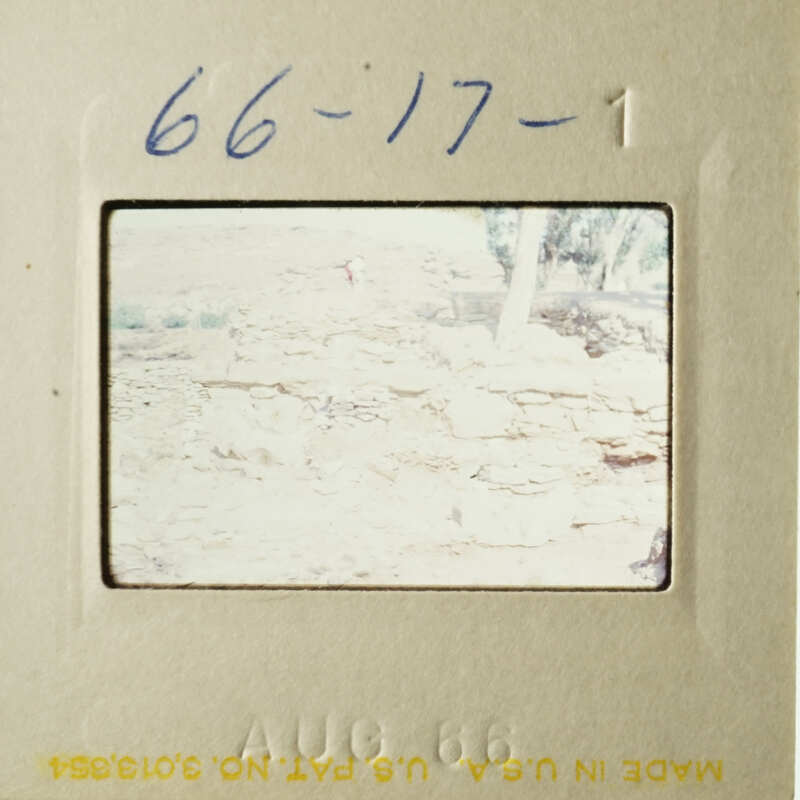 An image showing a vintage photograph with a handwritten note, depicting an outdoor scene with a person and a rocky landscape.