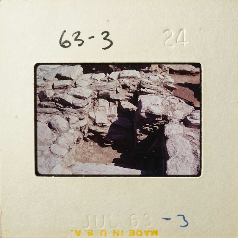 Old photograph of a rocky cave entrance with sunlight streaming through.