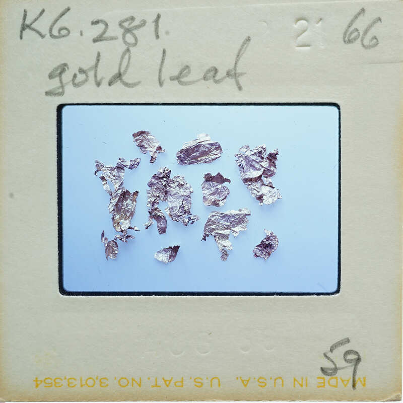 Gold leaf samples on a blue background, with labels and writing indicating scientific analysis or identification.