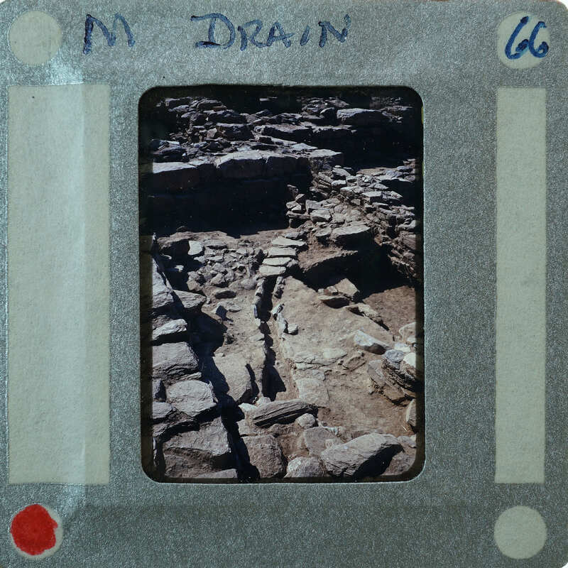 A photograph of a stone path with ruins, set within an old-fashioned film strip border.