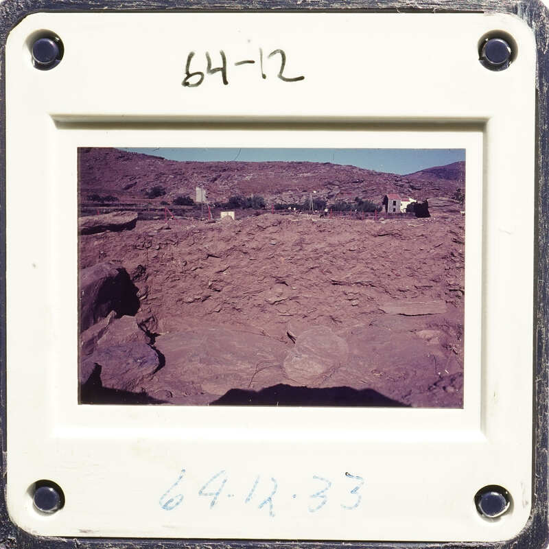 A photograph of an outdoor dirt area with rocky terrain and sparse vegetation.