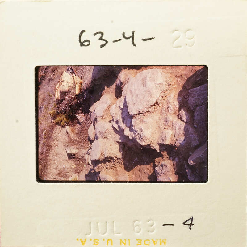 Rocky cliff with vegetation, captured on film.