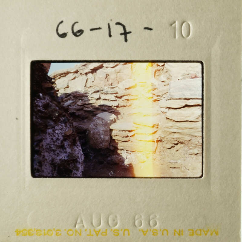 A vintage photo of a rocky wall with a yellowish light on it.