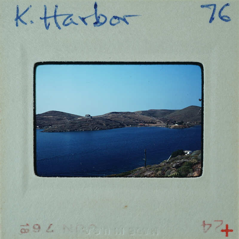 A vintage photograph of a serene harbor with calm waters and distant hills.