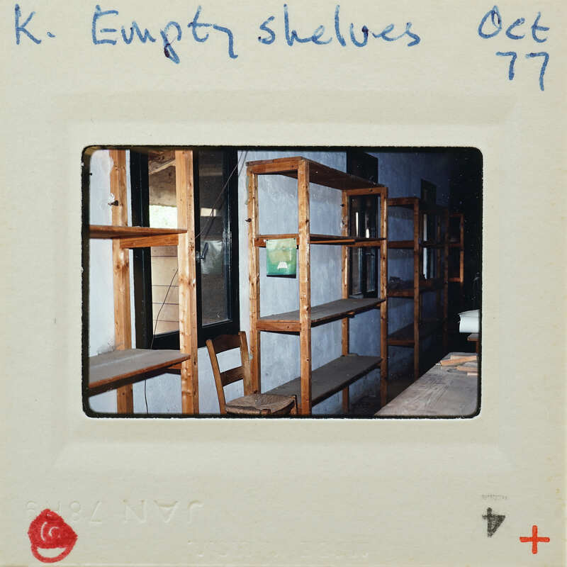 Empty wooden shelves inside a building, captured on a Polaroid photo with handwritten notes.