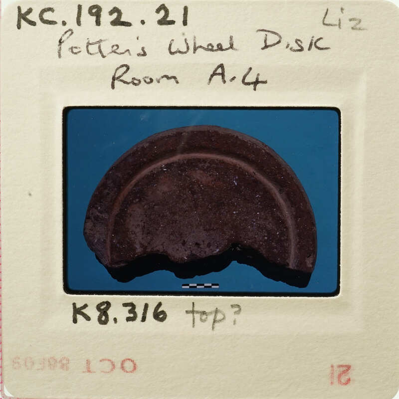 Broken circular object on blue background with handwritten notes and stamps.